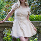 Toasted Crème Custard Dress | Short Sleeve Muslin Mini Dress With Adjustable Side Ties And Wooden Bead Accents